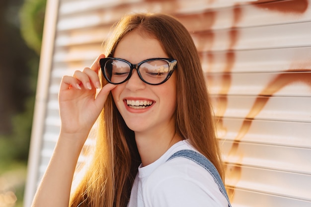 朝の日差しでスタイリッシュなメガネの若い肯定的な魅力的なかわいい女の子