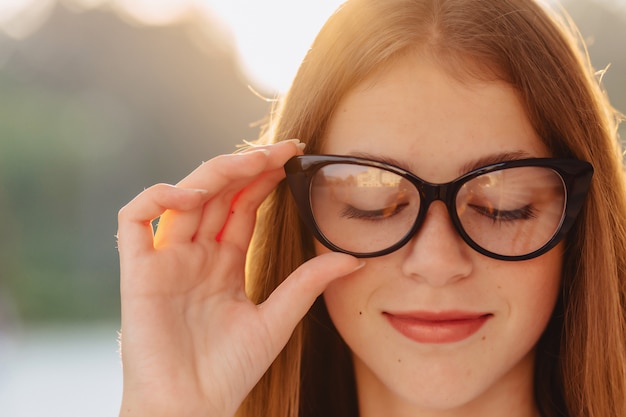 Young positive attractive pretty girl in stylish glasses at morning sunshine