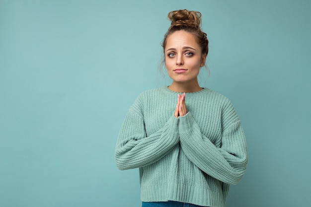 young positive beautiful blonde woman with sincere emotions wearing casual blue pullover