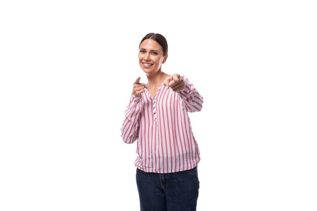 Young positive brunette assistant woman with ponytail hairstyle dressed in a striped blouse on a