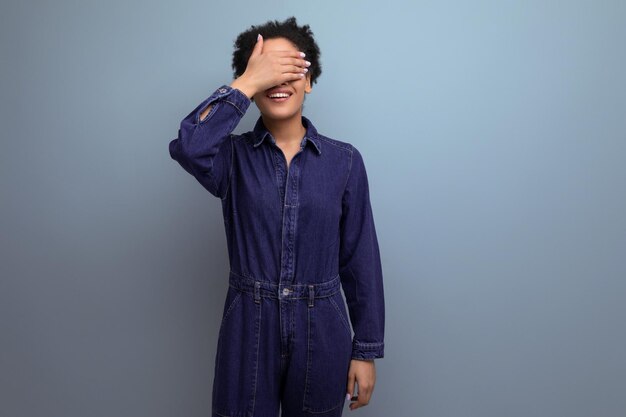 Young positive brunette latin woman with afro hair gathered in a ponytail dressed in a blue stylish