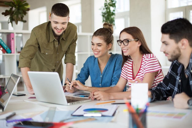 young positive business people joyfully working on laptop together group of smiling men and women spending time at work in modern cozy office