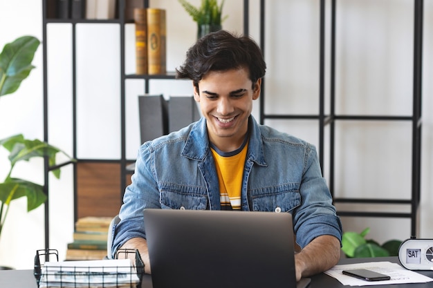 Young positive caucasian man using computer for video communication with coworkers or home office or watch the online course. Video conference concept