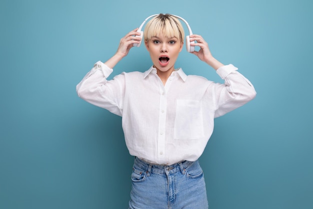 Young positive caucasian woman with a short haircut dressed in a white shirt and jeans uses wireless