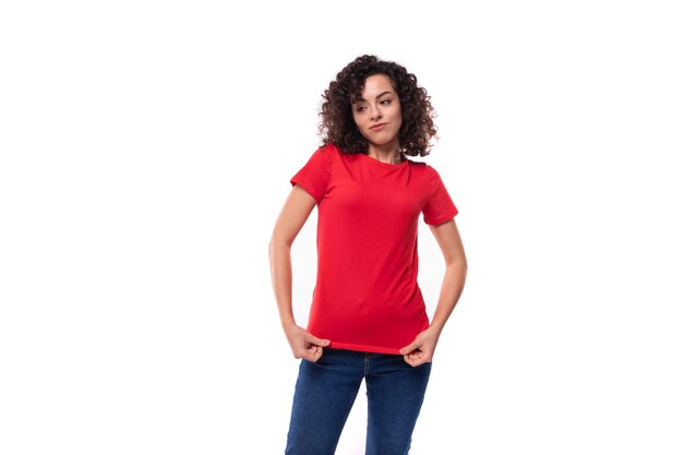 Photo young positive curly brunette woman dressed in a red tshirt in corporate color