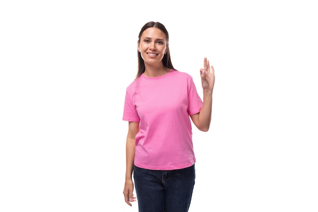 Young positive goodlooking woman with black hair is wearing a pink tshirt holding her hand up