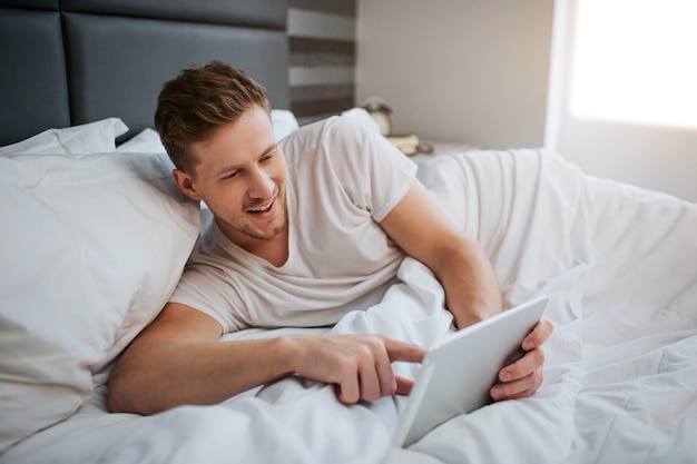 Young positive man lying in bed early morning