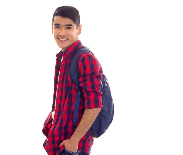 Young positive man with black hair in jeans white Tshirt and checkered shirt with blue backpack