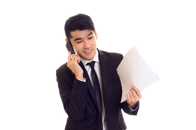 Young positive man with black hair in white shirt and black suit with tie holding papers