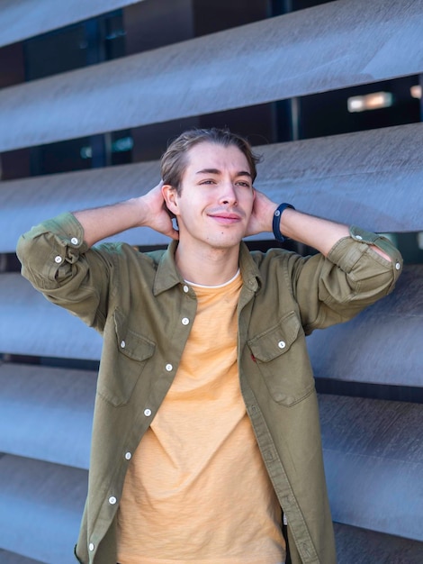 Foto giovane uomo positivo in maglietta gialla e giacca verde che fissa i capelli