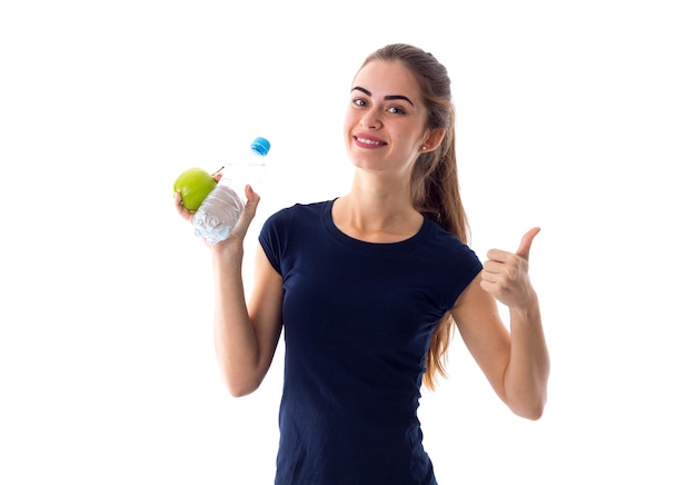 Young positive woman in blue Tshirt with centimeter around her neck holding green apple in studio