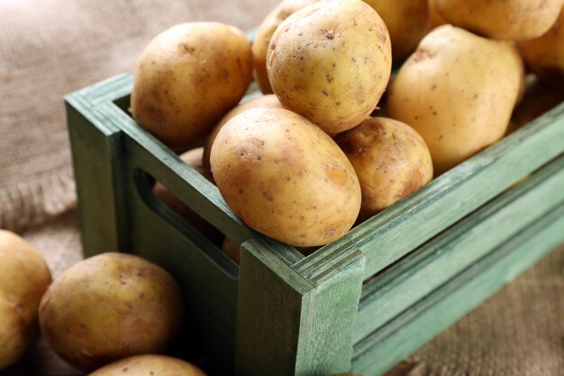 Young potatoes in crate on table close up