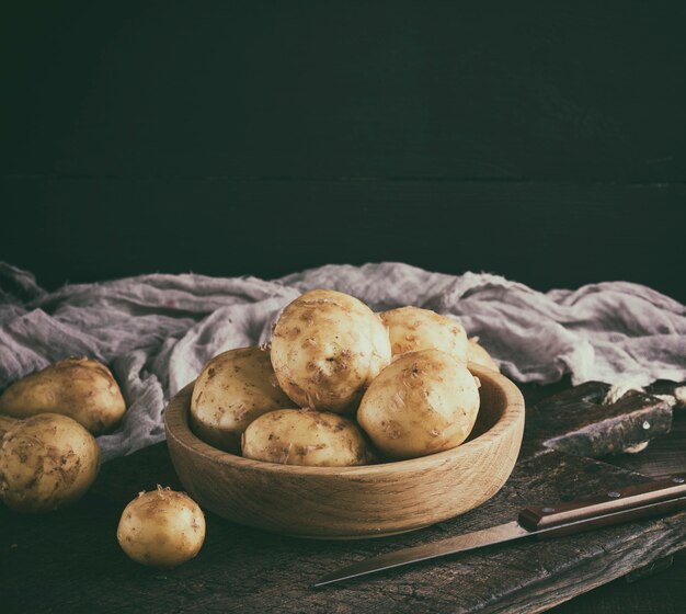  young potatoes in the peel lay in a wooden bowl 