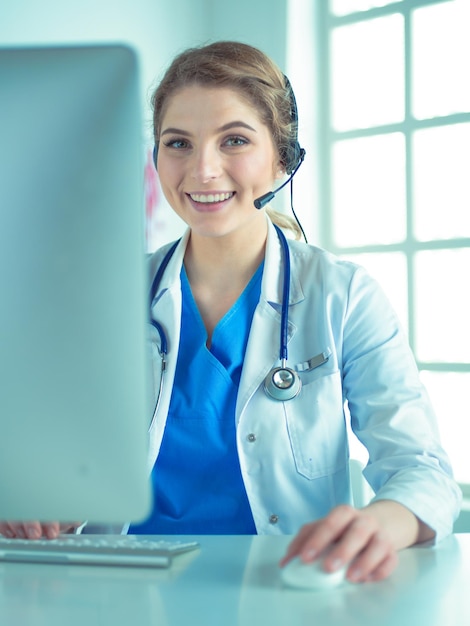 Young practitioner doctor working at the clinic reception desk she is answering phone calls and sche