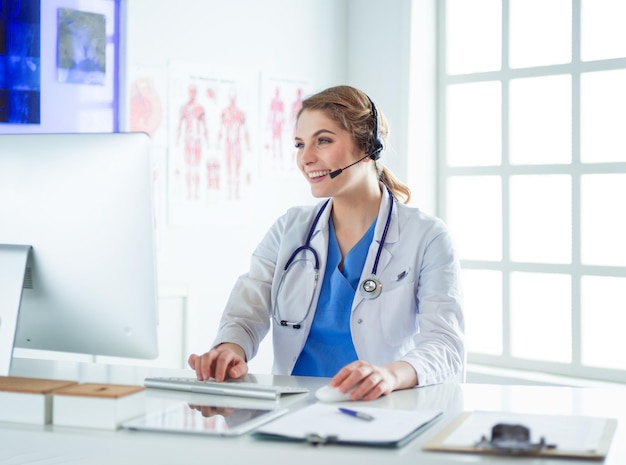 Young practitioner doctor working at the clinic reception desk she is answering phone calls and sche