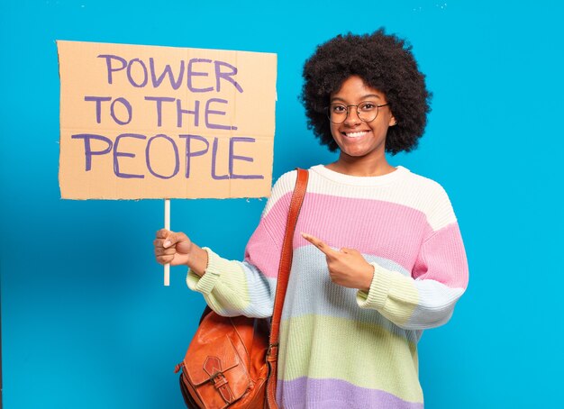 Foto giovane donna pre afro che protesta con uno striscione del potere al popolo