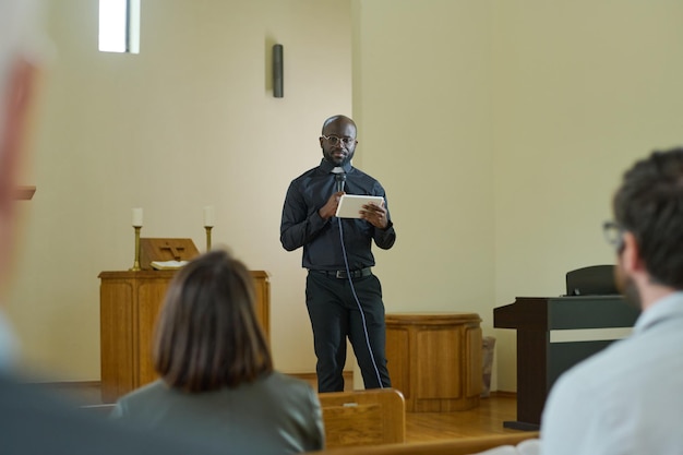 Young preacher in smart casualwear quotating verses from bible during sermon