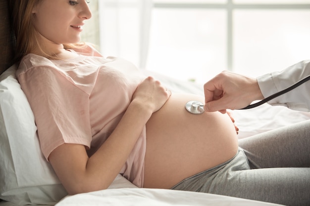 Young preganant woman expecting a baby resting on bed doctor visit