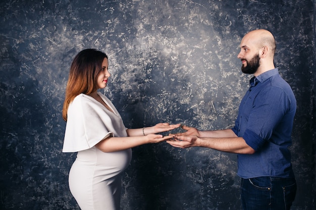 Young pregnant couple holding copyspace on the palm.