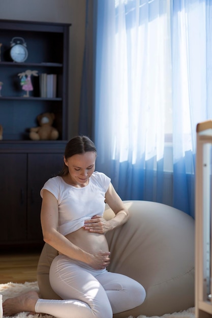 Young pregnant lady between 30 and 35 years old  caresses her her belly.