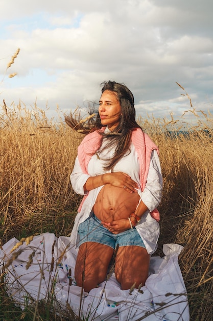 Photo young pregnant latin woman seated on a wheat field