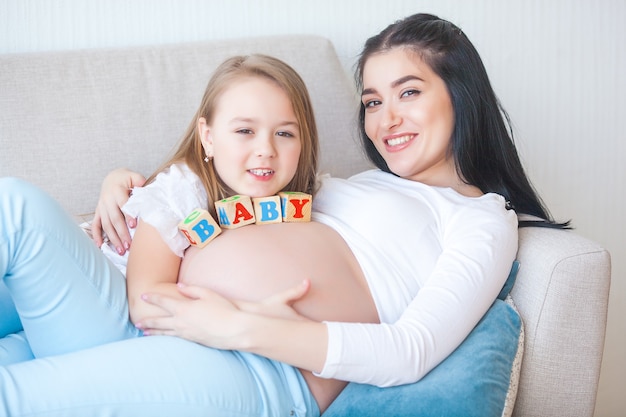 Young pregnant mother and her first child indoors