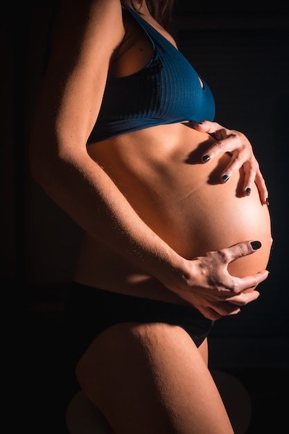 출산하려고하는 젊은 임산부. 배에 손을 대십시오. 일부 스튜디오 사진에서