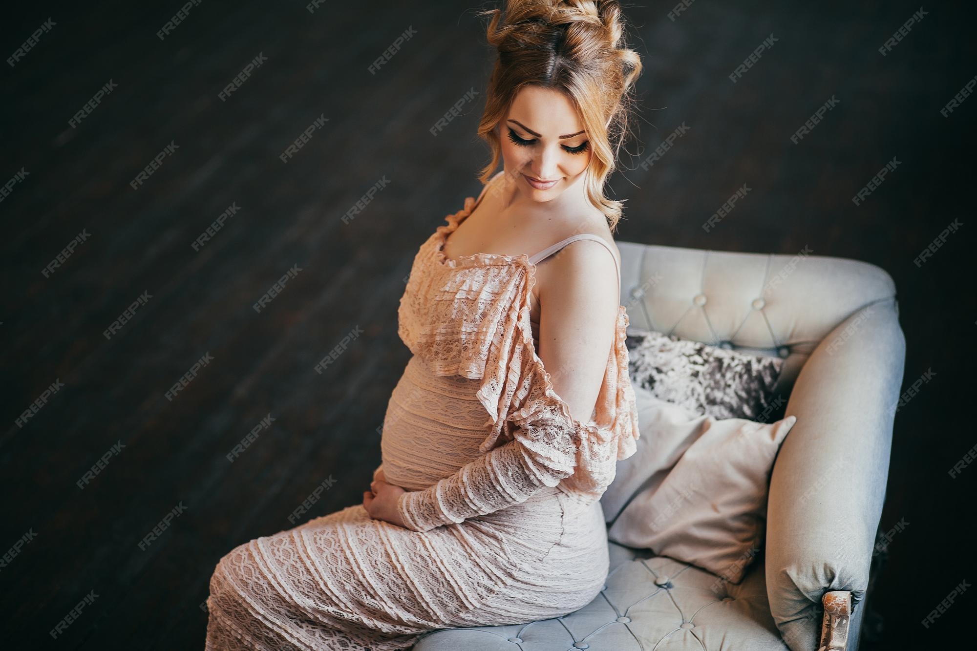 Premium Photo | A young pregnant woman in a beautiful dress is sitting in  the window
