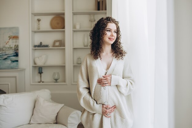 Young pregnant woman in a beige cardigan