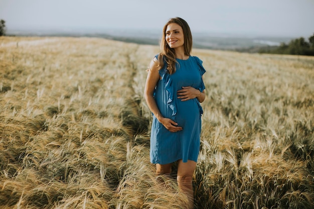 Young pregnant woman in blue dress in the summer field