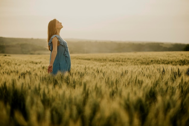 Young pregnant woman in blue dress in the summer field