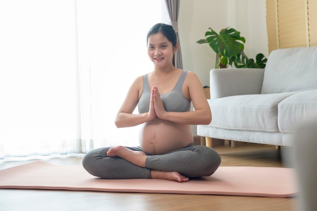 Giovane donna incinta che fa yoga a casa concetto di assistenza sanitaria e gravidanza