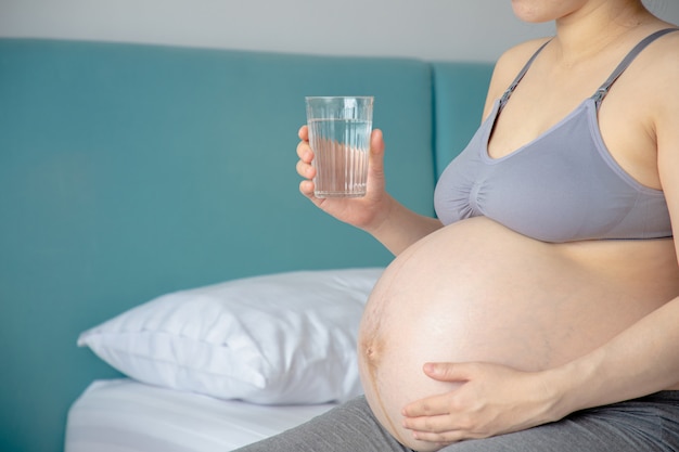 Young pregnant woman drinking water.