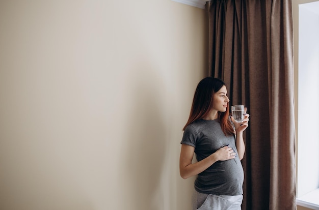 Young pregnant woman drinking water