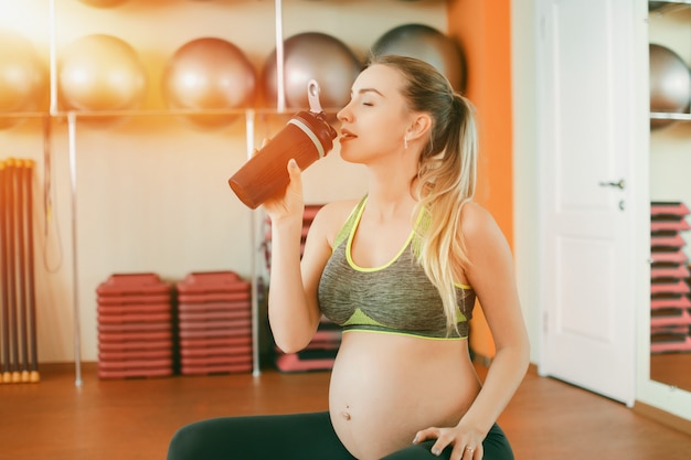 Young pregnant woman drinking water