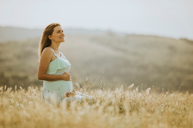Молодая беременная женщина в поле
