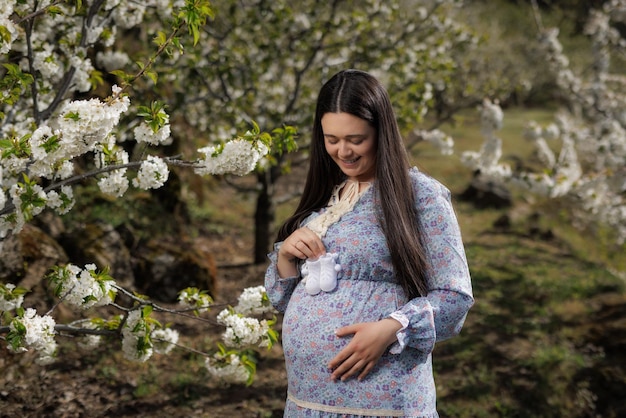 Young pregnant woman happily looks at the booties of her future baby