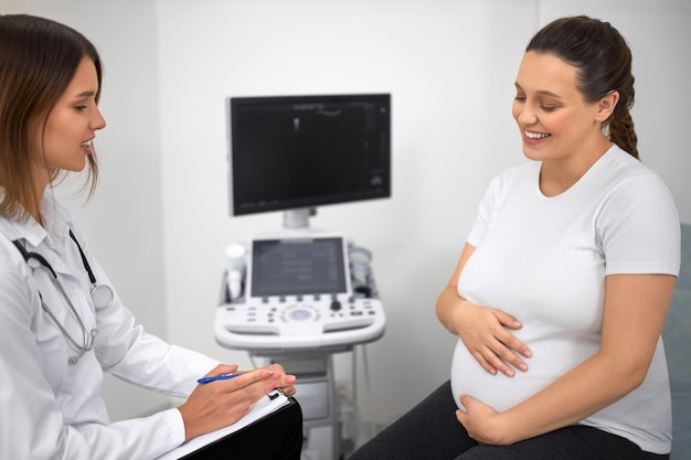 Giovane donna incinta avente consultazione medica con ginecologo femminile all'ospedale. assistenza sanitaria durante la gravidanza. visita regolare in clinica.