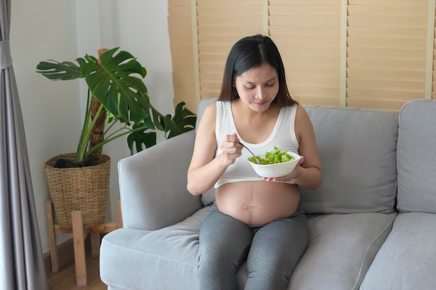 Young pregnant woman having salad at home healthcare and pregnancy care