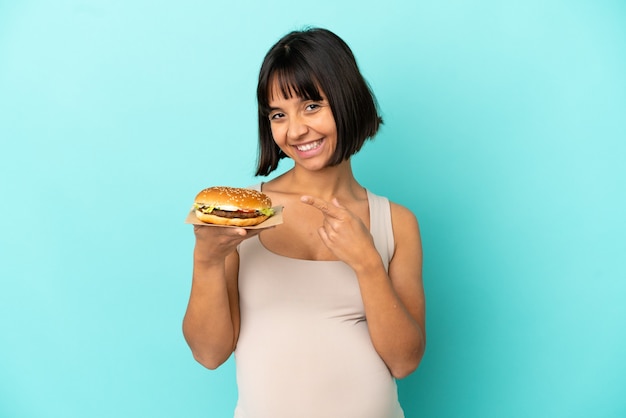 Young pregnant woman holding burge over isolated background