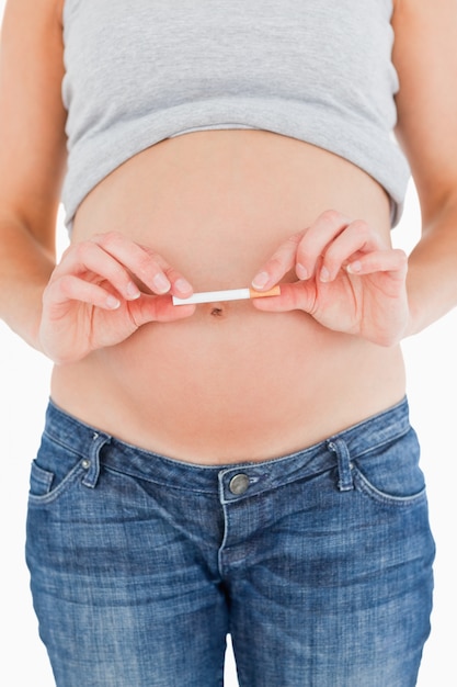 Young pregnant woman holding a cigarette while standing