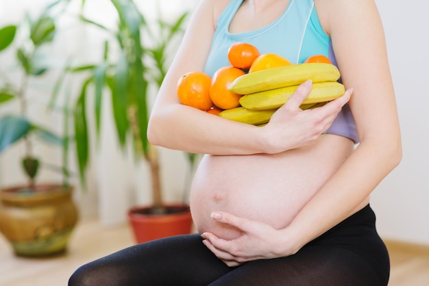 A young pregnant woman holding fruits