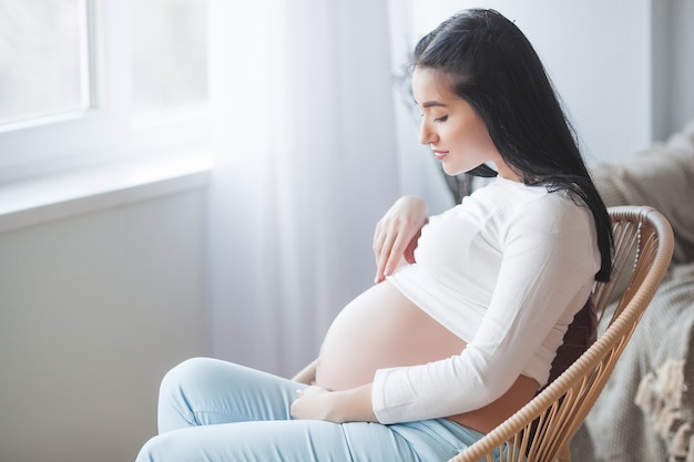 실내 젊은 임신 한 여자. 기대하는 여자의 근접 촬영 초상화입니다. 그녀의 작은 아기 탄생을 기다리는 아름 다운 여성.