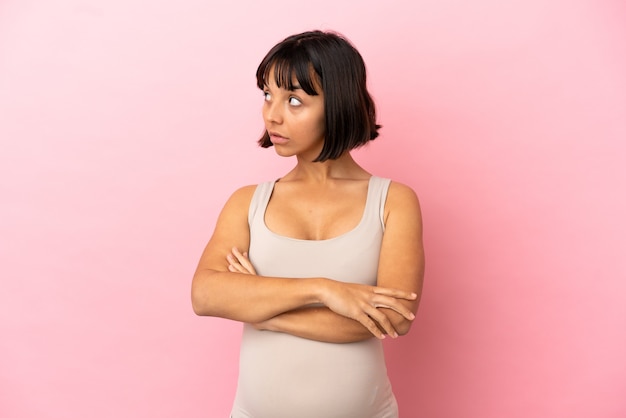 Young pregnant woman over isolated pink background keeping the arms crossed