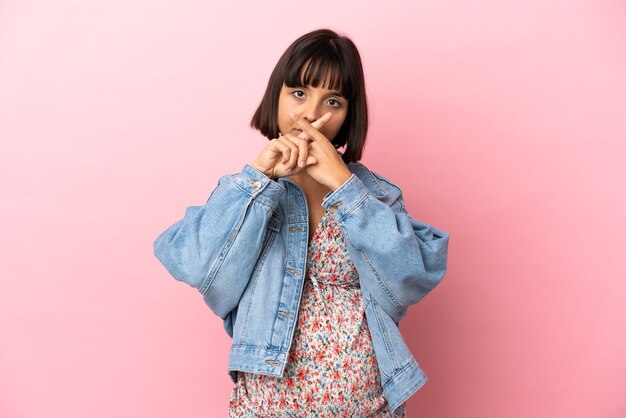 Young pregnant woman over isolated pink background showing a sign of silence gesture