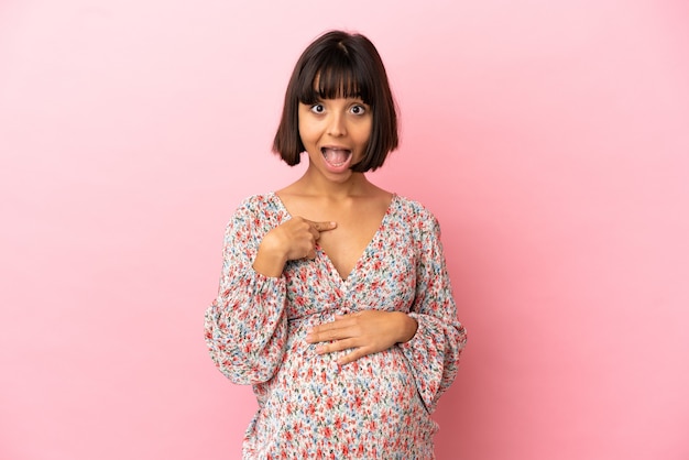 Foto giovane donna incinta su sfondo rosa isolato con espressione facciale a sorpresa