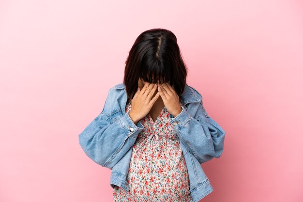 피곤하고 아픈 표정으로 고립 된 분홍색 배경 위에 젊은 임산부