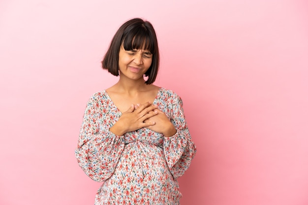 Photo young pregnant woman over isolated pink surface having a pain in the heart