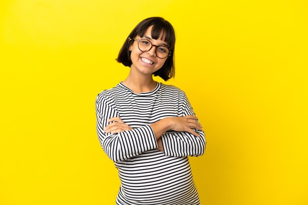 Young pregnant woman over isolated yellow background keeping the arms crossed in frontal position