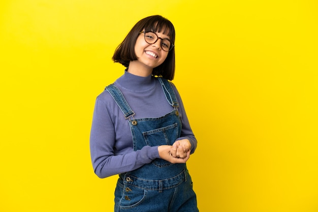 Young pregnant woman over isolated yellow background laughing